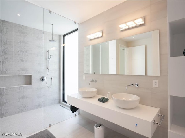 bathroom with vanity, tiled shower, tile walls, and backsplash