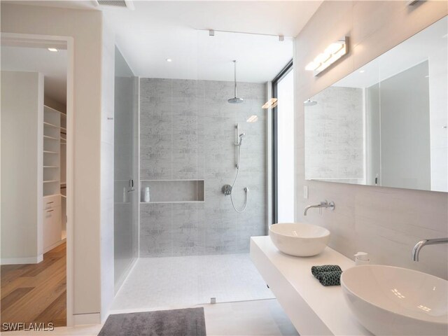 bathroom with hardwood / wood-style flooring, vanity, and a tile shower