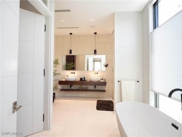 full bathroom featuring double vanity, a soaking tub, and a sink