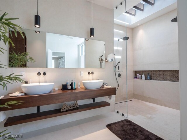 bathroom with vanity, tiled shower, tile walls, and backsplash