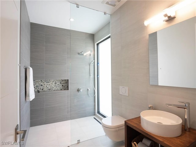 bathroom featuring vanity, tiled shower, tile walls, and toilet