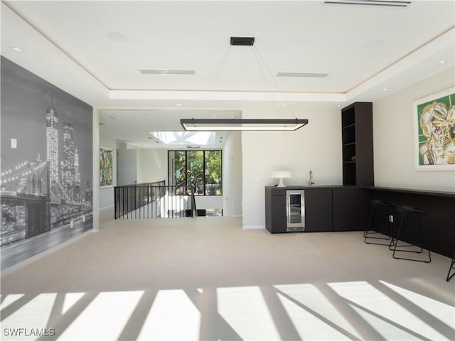 carpeted living room with a raised ceiling and wine cooler