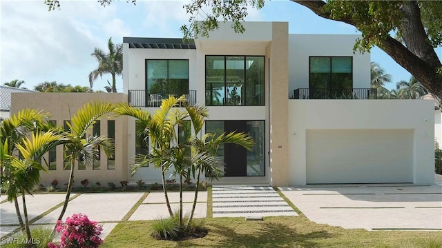 view of front of home featuring a garage, a balcony, and stucco siding