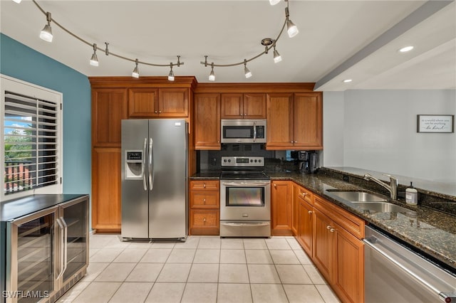 kitchen featuring sink, appliances with stainless steel finishes, light tile patterned flooring, beverage cooler, and dark stone counters