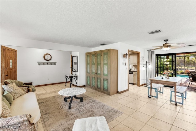 living room with ceiling fan, a textured ceiling, and light tile patterned floors