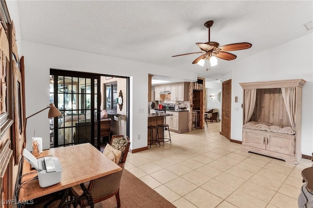 dining room featuring light tile patterned floors, ceiling fan, baseboards, and a textured ceiling