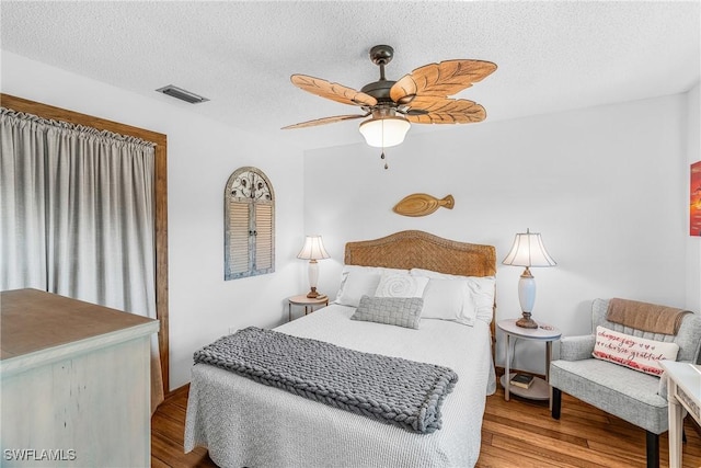 bedroom with visible vents, ceiling fan, a textured ceiling, and wood finished floors