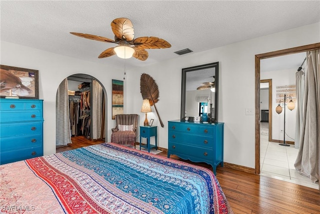 bedroom with ceiling fan, a textured ceiling, and light wood-type flooring