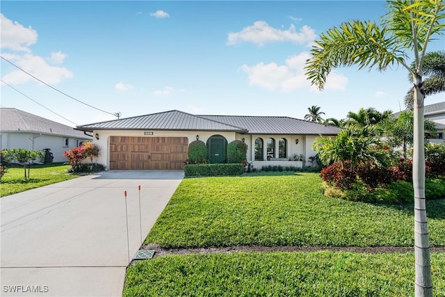 view of front facade with metal roof, a garage, concrete driveway, stucco siding, and a front lawn