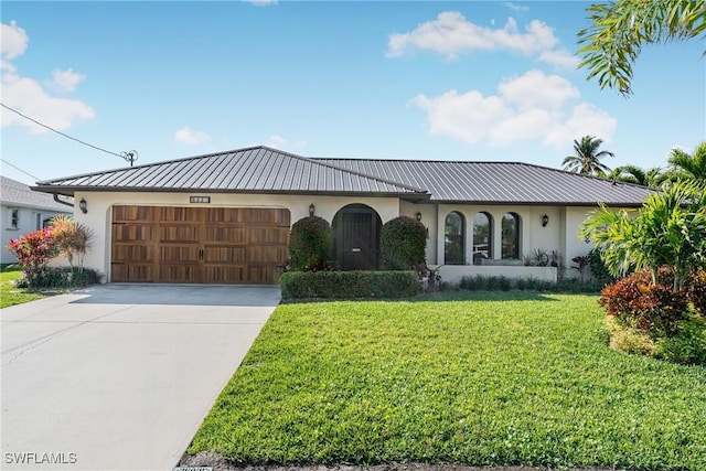 view of front of house with stucco siding, metal roof, a garage, driveway, and a front lawn