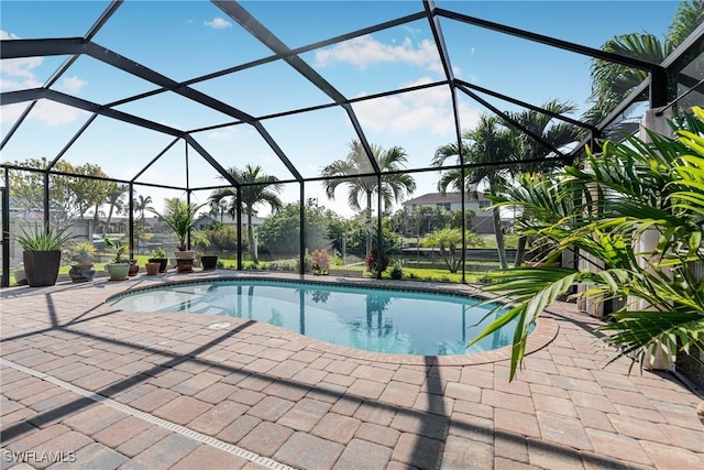 outdoor pool featuring glass enclosure and a patio