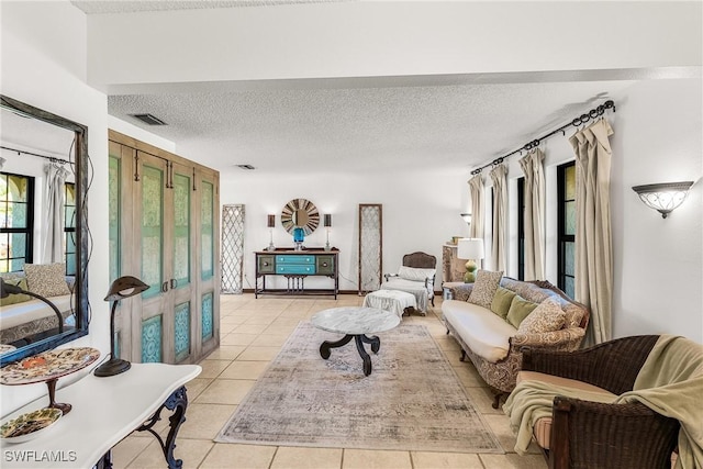 living area with visible vents, a textured ceiling, and light tile patterned floors