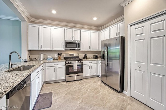 kitchen featuring light stone counters, stainless steel appliances, crown molding, white cabinetry, and a sink