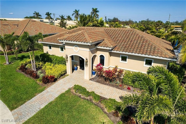 mediterranean / spanish home with driveway, stucco siding, a tile roof, and a front yard