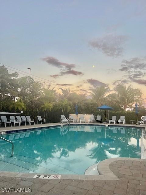 pool at dusk with a patio and a community pool