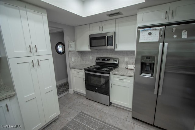 kitchen with stainless steel appliances, white cabinets, and light stone counters