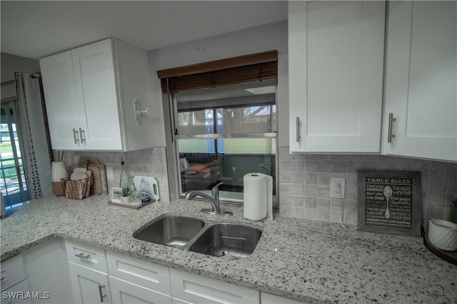 kitchen featuring white cabinetry, light stone countertops, sink, and a wealth of natural light