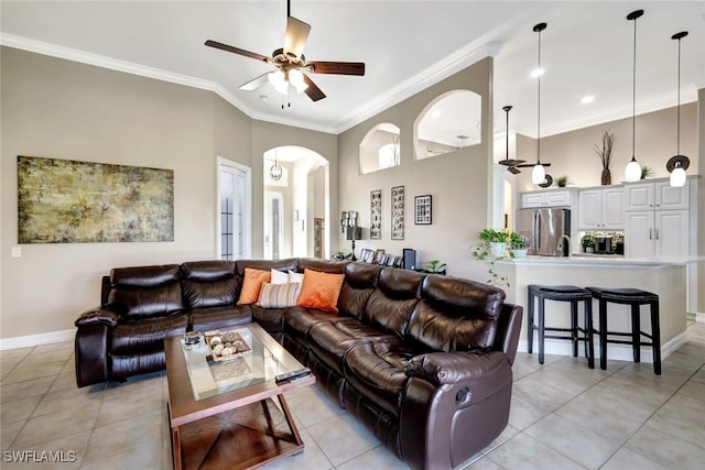 tiled living room featuring crown molding, ceiling fan, and a towering ceiling