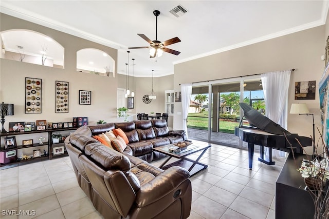 tiled living room with a towering ceiling, ornamental molding, and ceiling fan