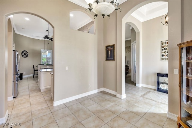 corridor featuring a towering ceiling, ornamental molding, a chandelier, and light tile patterned flooring