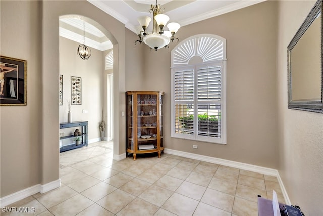 empty room featuring a high ceiling, ornamental molding, light tile patterned flooring, a raised ceiling, and a chandelier