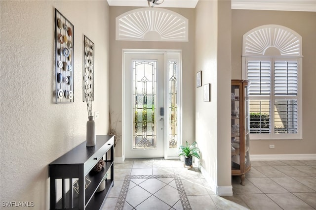 tiled foyer with ornamental molding and a healthy amount of sunlight