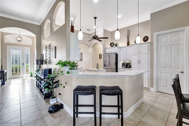 kitchen with hanging light fixtures, stainless steel refrigerator with ice dispenser, white cabinets, and crown molding