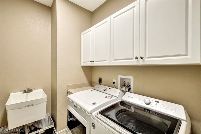 clothes washing area featuring cabinets, sink, and independent washer and dryer