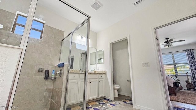 bathroom featuring vanity, a tile shower, ceiling fan, and toilet