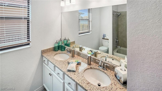 full bathroom with tiled shower / bath, vanity, and toilet