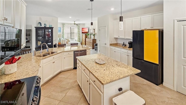 kitchen with pendant lighting, sink, appliances with stainless steel finishes, light stone countertops, and an island with sink