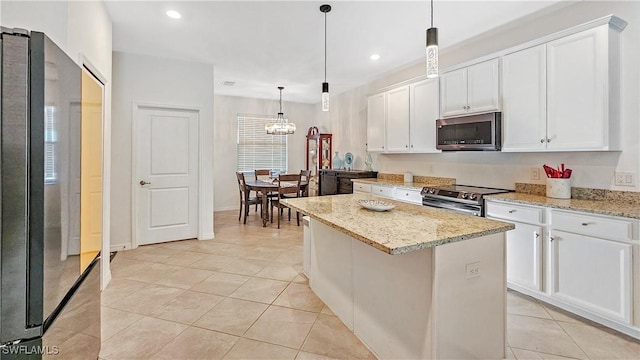 kitchen with light stone counters, appliances with stainless steel finishes, a kitchen island, pendant lighting, and white cabinets