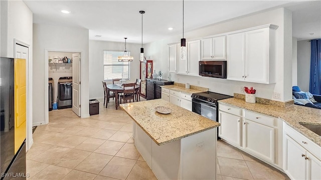 kitchen featuring appliances with stainless steel finishes, light stone countertops, white cabinets, washing machine and clothes dryer, and decorative light fixtures