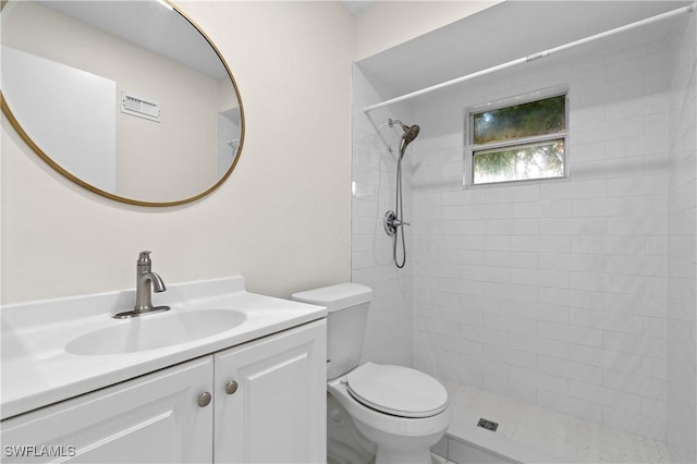 bathroom with tiled shower, vanity, and toilet