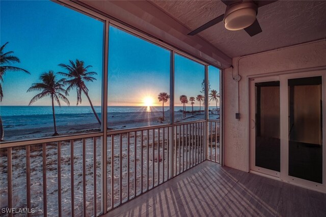 sunroom / solarium featuring a view of the beach, ceiling fan, and a water view