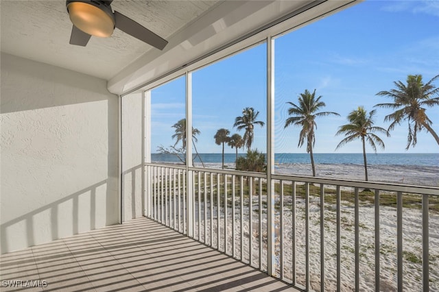 balcony featuring a water view, a beach view, and ceiling fan