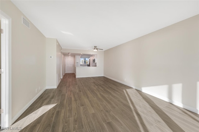 unfurnished living room featuring dark wood-style flooring, visible vents, ceiling fan, and baseboards