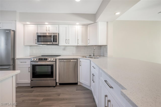 kitchen featuring white cabinets, light stone counters, stainless steel appliances, and a sink