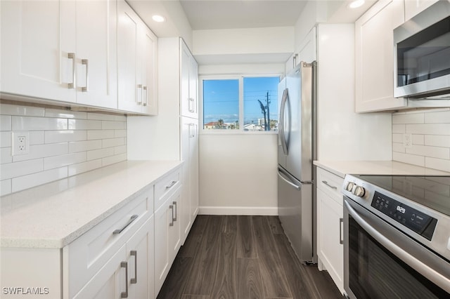 kitchen featuring dark wood-style flooring, stainless steel appliances, backsplash, white cabinets, and baseboards