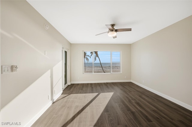 unfurnished room featuring dark wood-style floors, ceiling fan, and baseboards