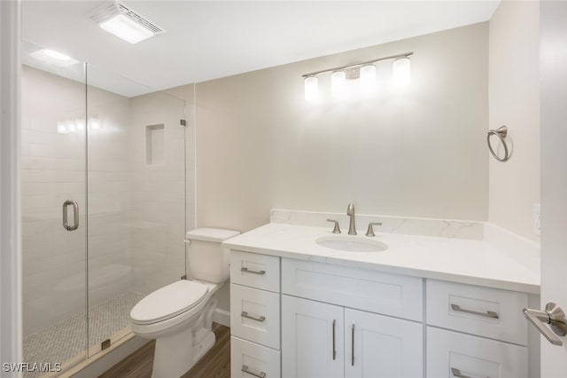 bathroom with a stall shower, visible vents, toilet, wood finished floors, and vanity