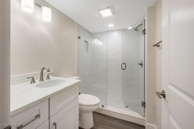 full bathroom featuring toilet, wood finished floors, visible vents, vanity, and a shower stall