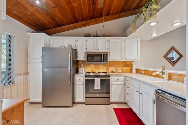 kitchen with appliances with stainless steel finishes, white cabinetry, sink, light tile patterned floors, and wood ceiling