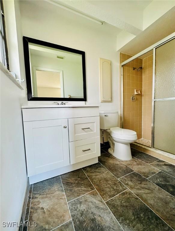 bathroom featuring an enclosed shower, vanity, and toilet