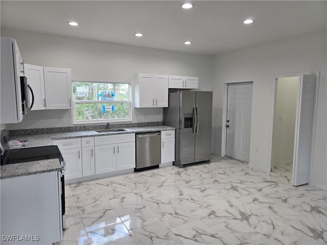 kitchen with light stone countertops, white cabinetry, appliances with stainless steel finishes, and sink