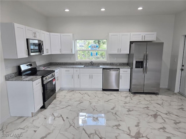 kitchen with white cabinetry, stainless steel appliances, sink, and stone counters