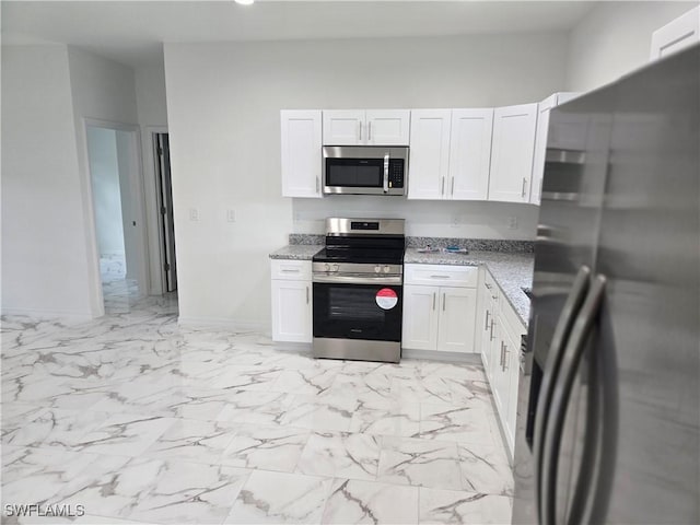 kitchen with stainless steel appliances, white cabinetry, and light stone counters