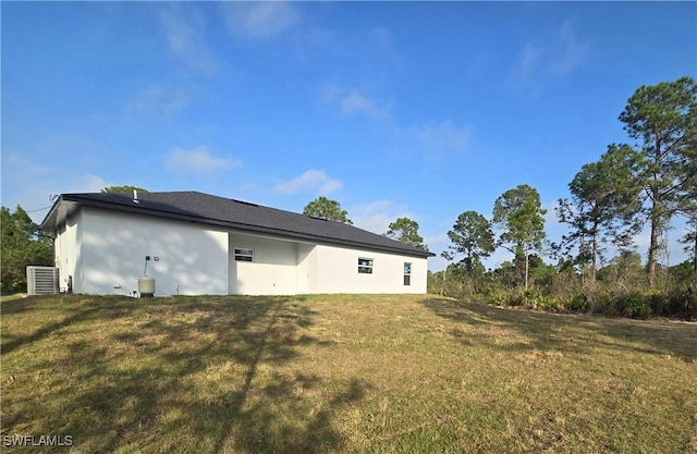 rear view of house featuring a lawn and central air condition unit