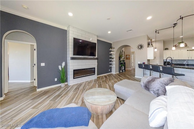 living room with ornamental molding, a fireplace, and light hardwood / wood-style flooring