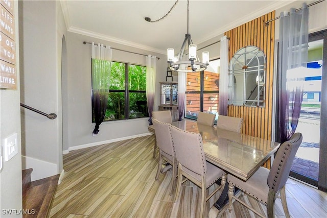 dining space featuring ornamental molding, light hardwood / wood-style flooring, and a notable chandelier